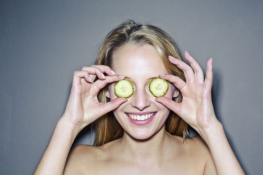 Young woman with cucumber slices covering eyes -фото