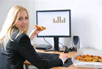 Девушка ест перед компьютером