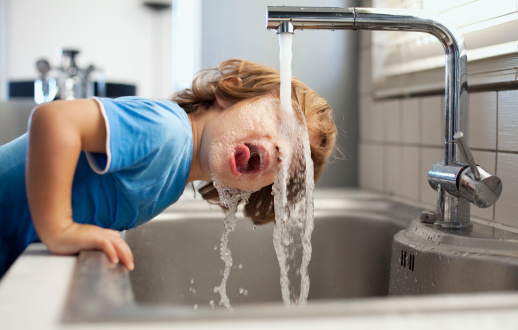 мальчик пьет воду из-под крана - фото