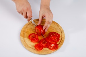 Нарізання помідорів на обробній дошці.
