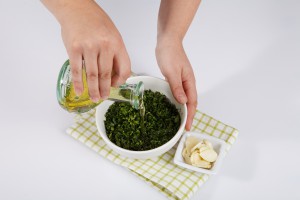 Смешивание нарезанной зелени с оливковым маслом - фото