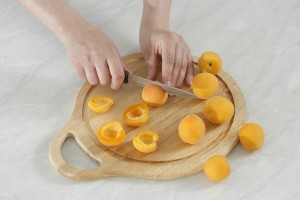 Розрізання абрикосів на обробній дошці.