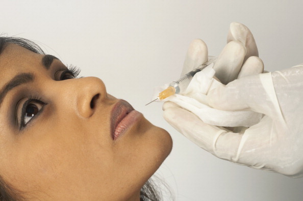 Doctor injecting collagen into young womans lip