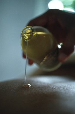 A therapist pouring therapeutic herbal oil onto a patient's