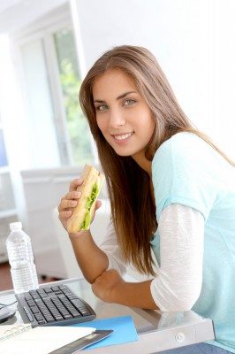 Жінка їсть бутерброд.