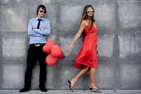 Young couple in sunglasses posing near wall