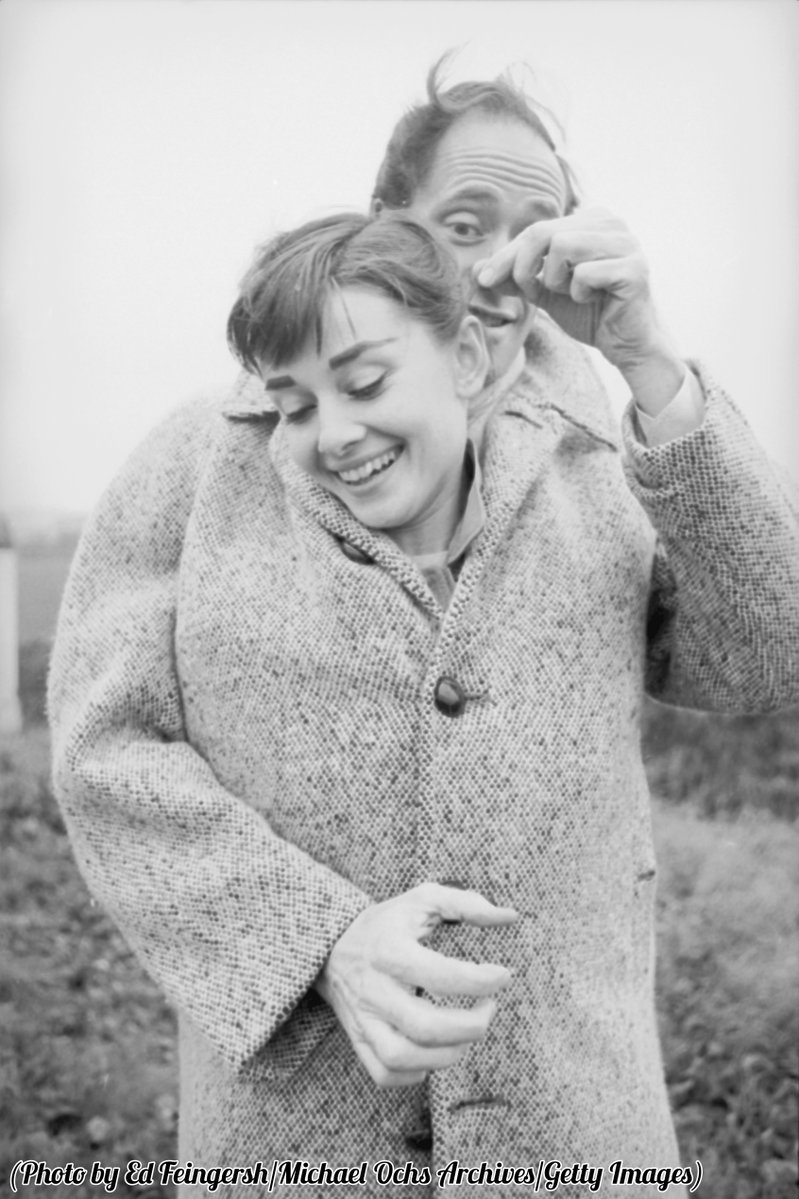 Audrey Hepburn and Mel Ferrer share a coat on a country road outside Paris, 1956.