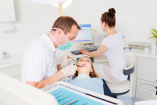 Dentist working on patients teeth - фото