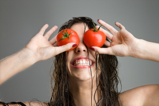 Woman with tomatoes covering her eyes -фото
