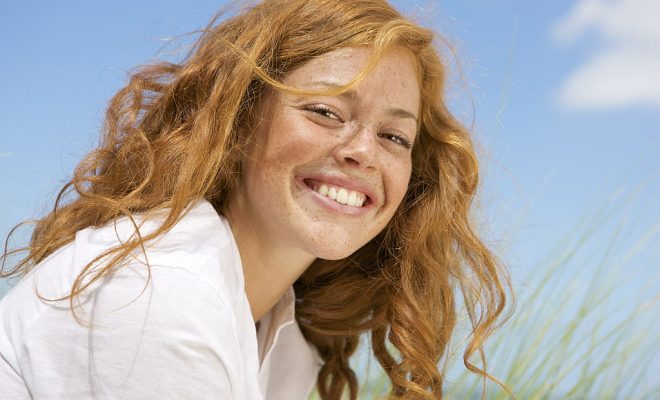 Netherlands, Vrouwenpolder, Young woman on beach, smiling, close-up - фото