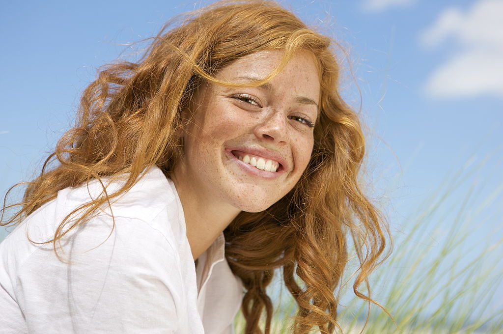 Netherlands, Vrouwenpolder, Young woman on beach, smiling, close-up - фото