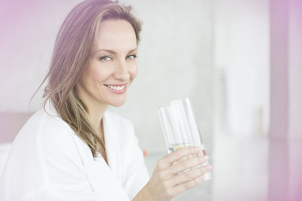 Woman having glass of water in bedroom - фото