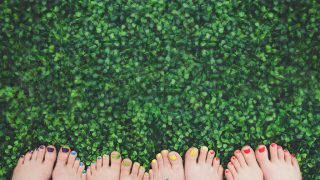 Close up of painted toenails or girls in grass - фото