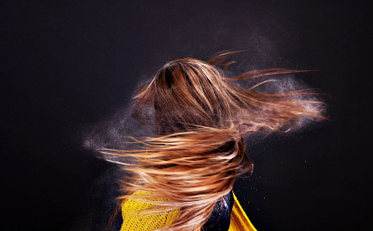 Powder blowing out of twirling womans hair - фото