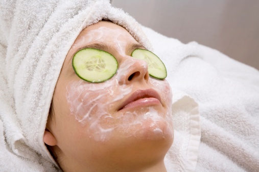 Young woman with face mask and cucumber slices, close-up - фото
