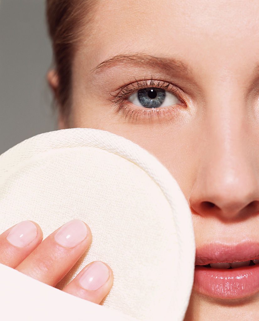 Woman using loofah pad on her face-фото