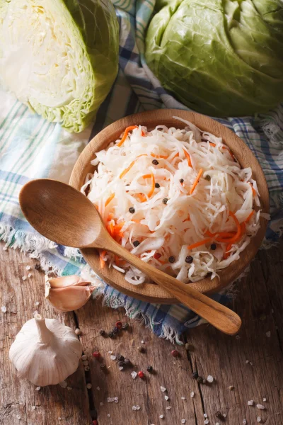 sauerkraut and carrots in a wooden plate vertical top view