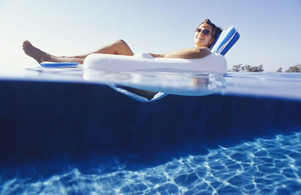 Woman lying in floating chair, surface view - фото